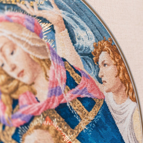 Gobelenas — artimas kadras, atskleidžiantis Mergelės ir angelo siuvinėjimo detales bei mėlynos ir auksinės spalvų tekstūrą
