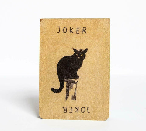 Joker korta iš kraft popieriaus su ranka piešta juoda katė, stovinti vertikaliai ant atramos, senovinio stiliaus