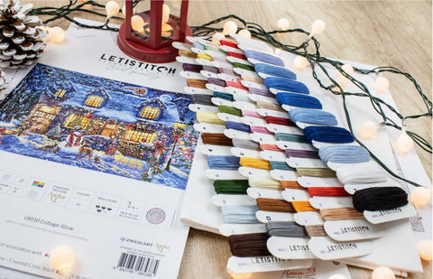 Siuvinėjimo rinkinys Letistitch 'Cottage Glow' su ~40 spalvų siūlų kortelėmis ir spausdinta kryželių schema kampu, fone LED girlianda
