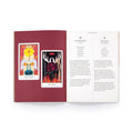 Tarot kortos ir instrukcijų knyga: atverstas leidinys su burgundišku fonu ir dviem kortomis Temperance ir The Devil bei paaiškinančiu tekstu