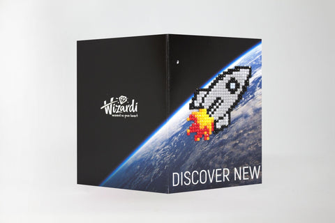 Atvirukas Wizardi juodas, sulankstytas, priekiniame plane mozaikinė raketa su liepsna virš Žemės ir užrašu DISCOVER NEW