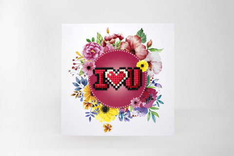 Atvirukas su rožiniu centru ir pikseliniu „I ♥ U“ užrašu, apsuptas spalvingų gėlių vainiko kaip priekinis dizainas