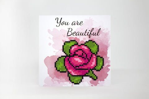 Atvirukas su rože ir mozaikiniais deimantėliais, rožinės ir žalių tonų, kviečiantis užrašu You are Beautiful priekinėje dalyje