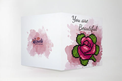 Atvirukas Wizardi su rožiniu akvarelės fonu ir rausva karoliukų rože, sulankstytas, matomas užrašas "You are Beautiful"