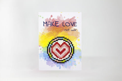 Atvirukas su akvareliniu geltonai‑mėlynu fonu, kristalais puoštą pikselinę širdį centre ir užrašu MAKE LOVE not war