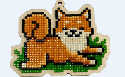 Pakabukas lape ant medinio pagrindo su oranžiniais ir baltais deimantinės mozaikos karoliukais, matoma kabliuko anga