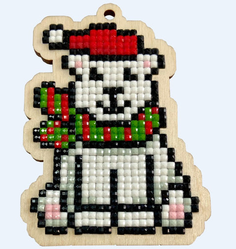 Kalėdinis medinis pakabukas: baltas lokys su raudona kepure ir žalia šalikė, smulkių blizgių karoliukų mozaika ir kabinimo skylutė, priekinis kampas