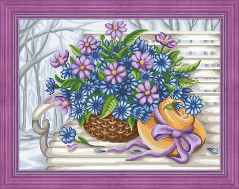 paveikslas gėlių krepšelis su mėlynomis ir violetinėmis gėlėmis, šviesiai geltona skrybėlė su violetine juosta ir violetinis rėmas, dekoruoti pavasario interjerui
