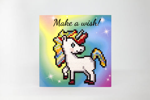 Deimantinė mozaika vienaragis su vaivorykštės griva ir blizgančiais kvadratėliais, kvadratinė kortelė su spalvotu fone ir "Make a wish" užrašu