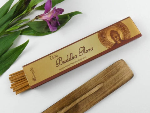 Smilkalai Buddha Flora masala, aukso dėžutė su apie 20 lazdelių, medinis laikiklis ir purpurinė gėlė fone