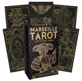 Tarot kortos Marseille Gold & Black leidimas — juoda dėžutė su aukso linijų iliustracija ir kelios aukso‑juodos didžiosios arkos kortos fone