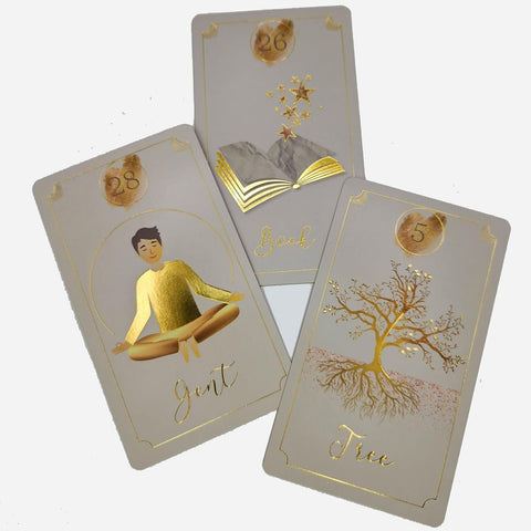 Kortų rinkinys su auksine folija, trys priekinių pusių kortos: meditacija (28), atvira knyga (26) ir medis su šaknimis (5), parodytos iš viršaus-trikampiu.