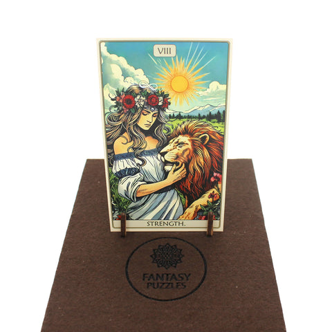 tarot korta Stiprybė ant medinio stovo, ryški iliustracija su liūtu, padėta ant rudos Fantasy Puzzles dangos