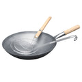 Produktų puslapyje rodoma anglinio plieno wok keptuvė su medine rankena ir tinkline mentele, fotografuota iš įstrižo kampo, komplektas