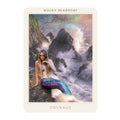 tarot korta „Drąsa“ (Rocky Seashore) — undinė su žydrai‑purpurine uodega ant audringų uolų, fone rūkas, bangos ir jūržemėlapio motyvas