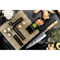 Sushi peilis kalvio rašto plieno geležte ir šviesia medine rankena, pateiktas šalia maki ritinėlių ant bambukinio kilimėlio