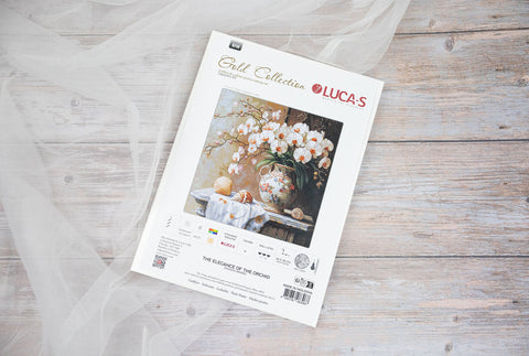 Siuvinėjimo rinkinys LUCA‑S su orchidėjų piešiniu, baltame dėkle 20×20 cm, pakuotės priekinė pusė ant šviesaus medinio fono