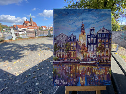 Mozaikos paveikslas Merejka, ryškių spalvų Amsterdamas, užbaigtas ant stovo, nufotografuotas lauke ant suoliuko prie upės su katedros fone