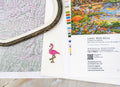 Skaičiuota kryželiu rinkinys Wild Africa – rodoma simbolių schema, spalvų paletė, siūlų lankelis ir rožinis flamingo smeigtukas