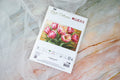 Kryželių rinkinys LUCA-S Graceful Tulips baltame voke su ryškiomis rožinėmis tulpėmis, parodytas iš viršaus ant marmuro fono