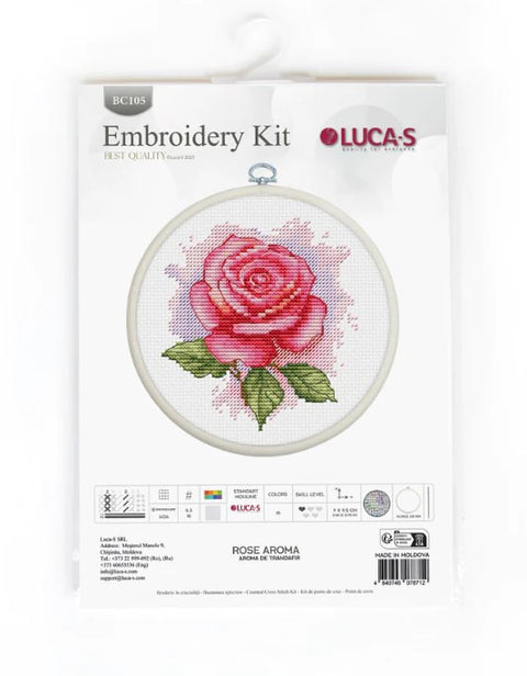 Siuvinėjimo rinkinys Rose Aroma su rožine rožės siuvinio kompozicija apvaliajame lankelyje ir matomu Lucas logotipu pakuotėje