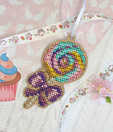 Pakabukas medinis lollipop su pastelinėmis perliukų granulėmis, spalvota spiralė priekyje ir balta pakabinimo juostelė