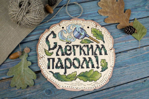 Pirties lentelė medinė, apvali, kryželiu siuvinėta su mėlyna gėle ir ąžuolo lapais, rodoma iš priekio, puiki dovanai