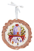 Siuvinėtas medinis kalėdinis žaisliukas su purpuriniu gaubtu ir spalvotais kabinamais ornamentais, pritvirtintas balta juostele