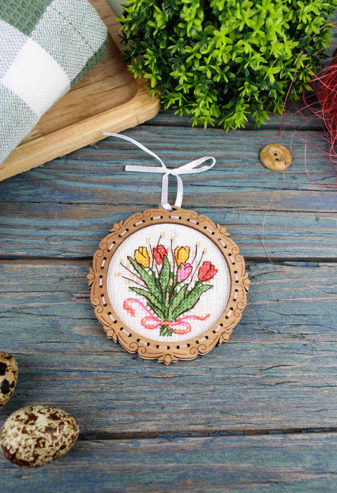 Siuvinėtas medinis ornamentas su spalvotomis tulpėmis ir baltu pakabinimo kaspinu, priekinis vaizdas ant mėlynos medinės lentos, 7 cm rėmas