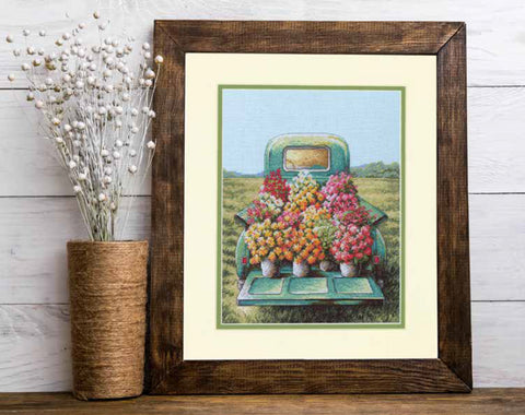 Įrėmintas plakatas su žaliu sunkvežimiu ir ryškiomis gėlėmis, medinis rėmas ant stalo, 30×40 cm