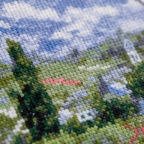 Kryželių rinkinys artimas planas: smulkūs siūlų kryželiai žalių ir mėlynų tonų peizaže, aiški tekstūra ir stitch detalė