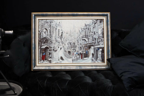Paveikslas siuvinėtas žiemos miesto peizažas sidabriniame rėme, apie 60×45 cm, eksponuotas ant juodo minkšto fotelio