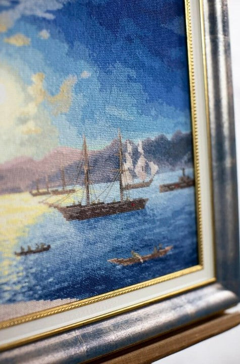 jūrinis paveikslas rėme su sidabriniu rėmu ir auksine juostele, arti kadro matoma drobės tekstūra ir burlaiviai