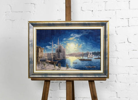 paveikslas mėlyna naktinė jūros panorama su laivais ir auksuotu sidabru rėmu, ~60×90 cm, eksponuotas ant medinio stovo prieš baltą plytų sieną