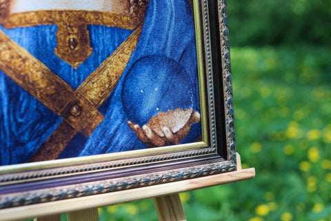 Ikona su auksinėmis ir mėlynomis detalėmis ornamentiniame rėme, artimas apatinio kampo kadras ant molberto lauke