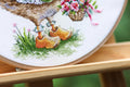 Siuvinys rankų darbo mediniame hoop rėmelyje – arti apžiūra geltonų klumpių ir smulkių kryžiuko siūlų detalių