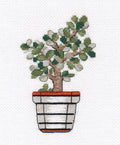 siuvinėtas bonsai su žaliais lapais ir rudu kamienu ant balto vazonėlio su oranžiniu kraštu, artimas priekinis planas, dekoratyvinė tekstilės detalė