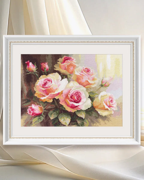 Kryželiu siuvinys rožės baltame dekoratyviniame rėme, užbaigtas 50×40 cm, rodomas iš priekio su švelniu apšvietimu