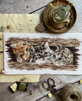 Siuvinėjimo rinkinys su trimis kačiukais, rudos ir pilkos spalvų paletė, 30×15 cm, stilizuota flatlay kompozicija su siūlais ir žirklėmis