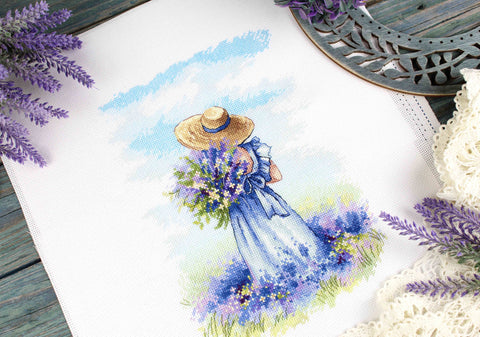 Siuvinėjimo rinkinys: detalus baigtas paveikslas — mergaitė mėlyname suknelėje su skrybėle ir levandomis, 30×40 cm artimas planas