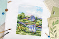 kryželių siuvinys su mėlynu nameliu ir trimis žąsimis ant žolės, parodo baigtą 30×30 cm dizainą ir spalvų detalumą