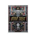 Star Trek žaidimo kortos dėžutė, juoda su auksiniu reljefiniu logotipu ir spalvotais futuristiniais ornamentais, priekinė pusė koncentrine erdvėlaivio grafika