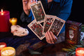 tarot kortos Del Toro, rankoje vėduojamos ir atskleidžiančios ryškias antikvarines iliustracijas, dekoratyvi dėžutė matoma šone