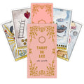 tarot kortos Tarot de Luz rožinė dėžutė su auksiniu ornamentu ir keliomis atverstomis iliustruotomis kortomis, pabrėžiant dizainą ir pakuotę