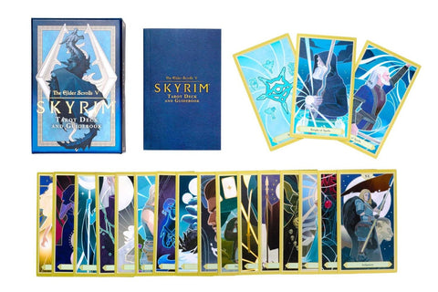 Skyrim tarot kortos komplektas su mėlynu dėklu ir vadovėliu, išdėstytos kortos su aukso krašteliais ir įvairiais piešiniais