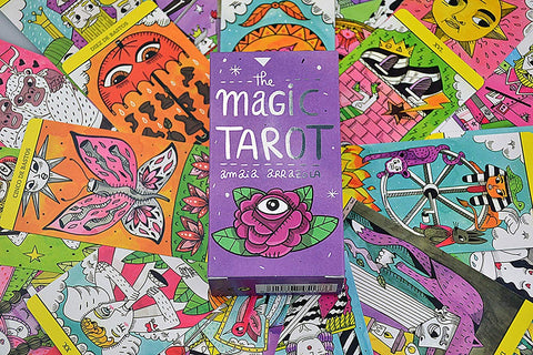 Tarot kortos Magic Tarot violetinėje dėžutėje ant spalvingo, rankomis iliustruotų kortų išklotės, centrinis vaizdas