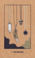 tarot korta The Magician ant rudo kraft popieriaus su kabančiais pakabukais — kristalu, plunksna, kaukole ir ornamentiniu medalionu