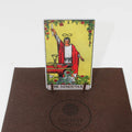 tarot korta The Magician stovi vertikaliai ant mažo medinio stovo ant rudos veltinio plokštelės su Fantasy Puzzles logotipu