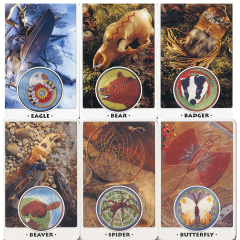 Karoliukų medaliukų rinkinys su šešiais gyvūnų motyvais (erelis, lokys, barsukas, bebras, voras, drugelis), pateiktas ant natūralių indėniškų rekvizitų fono