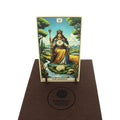 Tarot korta The Empress, priekis ant mažo medinio stovelio ant rudo vilnonio kilimėlio su Fantasy Puzzles logotipu
